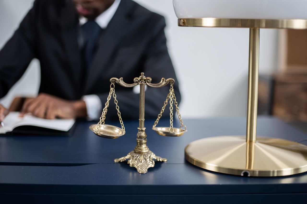services-01 Elegant legal office with a close-up of golden scales of justice on a sleek dark desk.